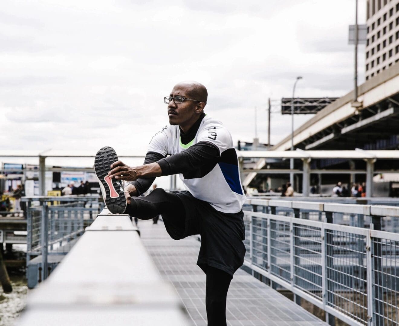 A man stretching on the side of a bridge.