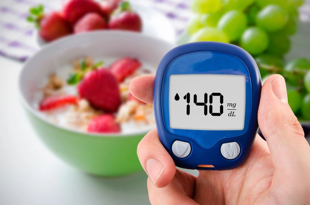 A person holding up a glucose meter in front of bowl of cereal.